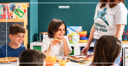 fermo immagine dello spot Albero della Vita con bambini che mangiano ed educatrice